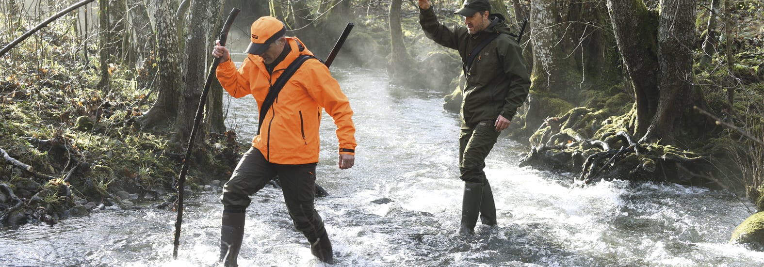 Deux chasseurs en tenue technique Hart traversant une forêt brumeuse, dont une veste orange haute visibilité